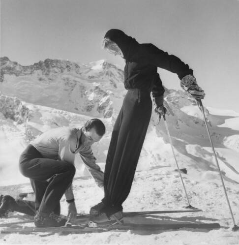 Emilio Pucci侯爵为身着Pucci滑雪服的Poppi de Salis夫人整理着装。摄于1947年，采尔马特。刊登于1948年的《时尚芭莎》，© Toni Frissel，由佛罗伦萨Emilio Pucci档案馆提供。